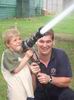 Volunteer and child using a fire hose